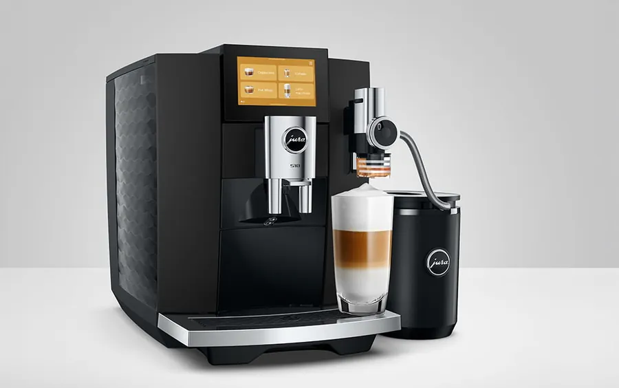 JURA S10 in Schwarz mit Touchscreen, Milchbehälter und einem geschichteten Milchkaffee im Glas